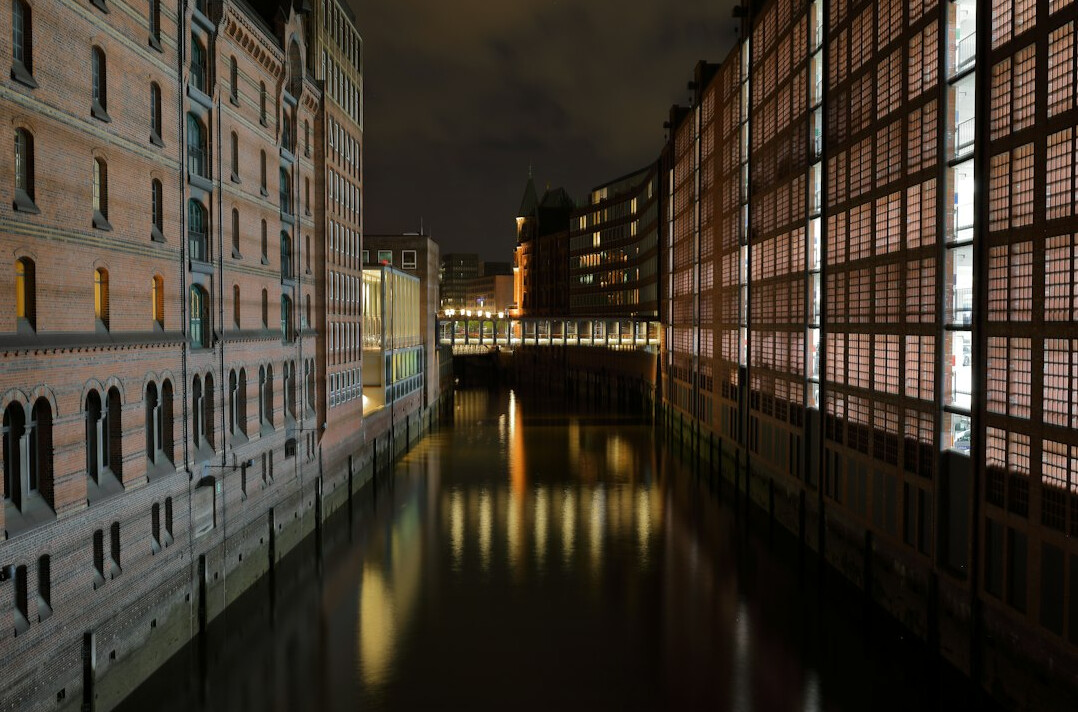 Brick warehouse facade with loading hatches above a canal at night